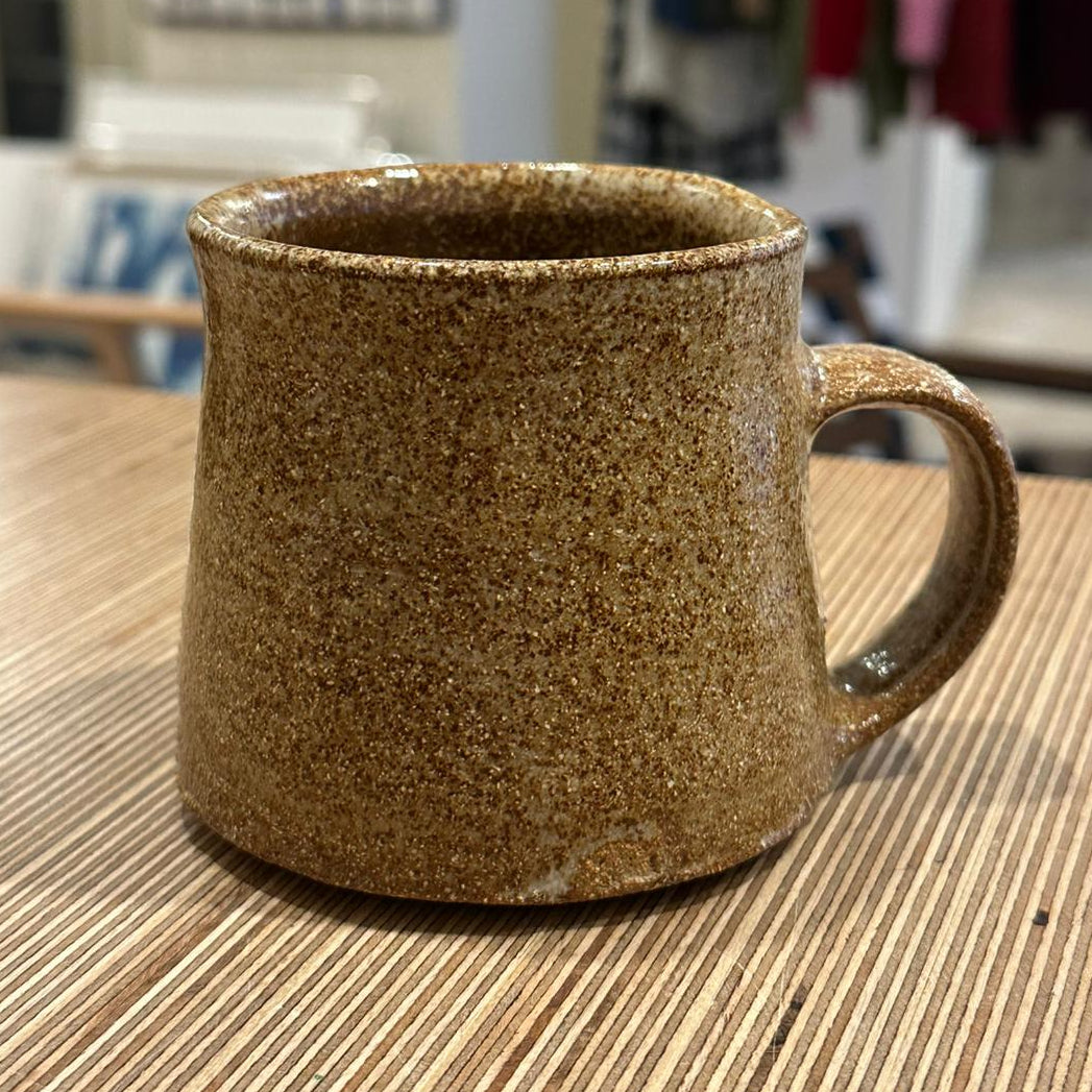 Brown speckled mug on a wooden surface with a blurred background