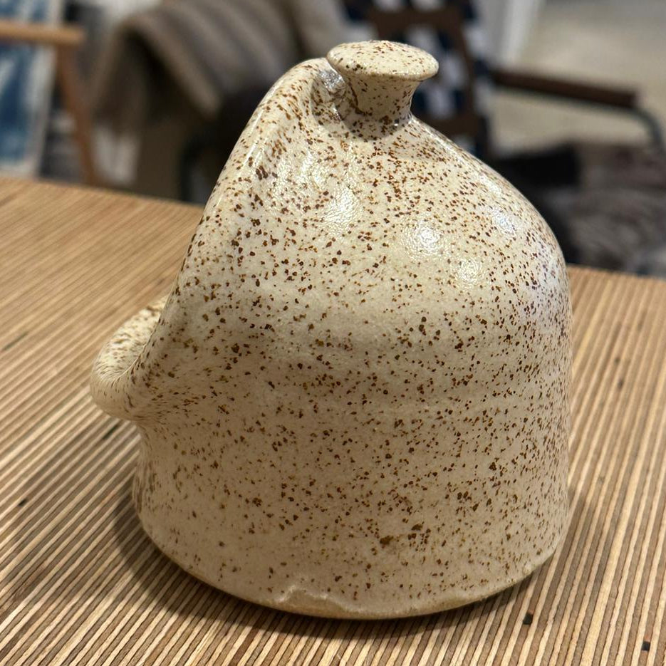 A white speckled salt pig on a wooden backgroud 