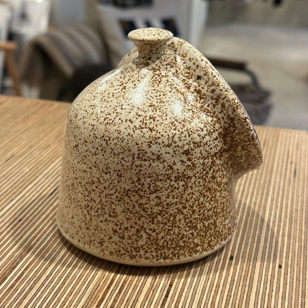 A white speckled salt pig on a wooden surface 