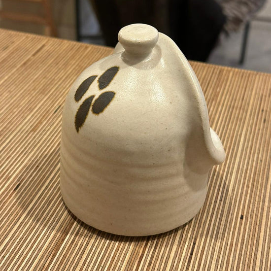 Ceramic container with leaf design on a wooden table