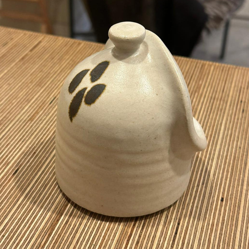 Ceramic container with leaf design on a wooden table