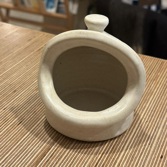 A salt pig in white on a wooden surface 