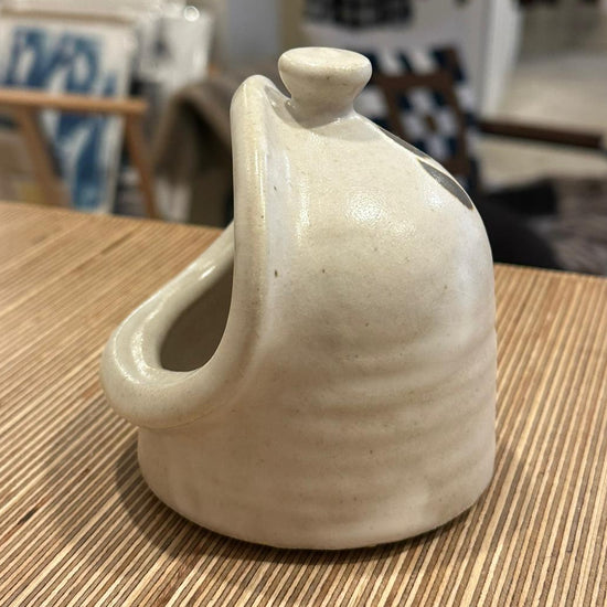 A white salt pig on a wooden surface 