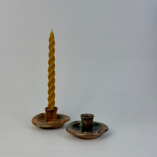 Two candle holders with a twisted candle on a gray background
