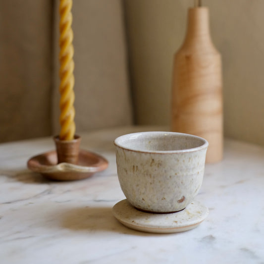 Speckled ceramic cup on a marble surface with a blurred background