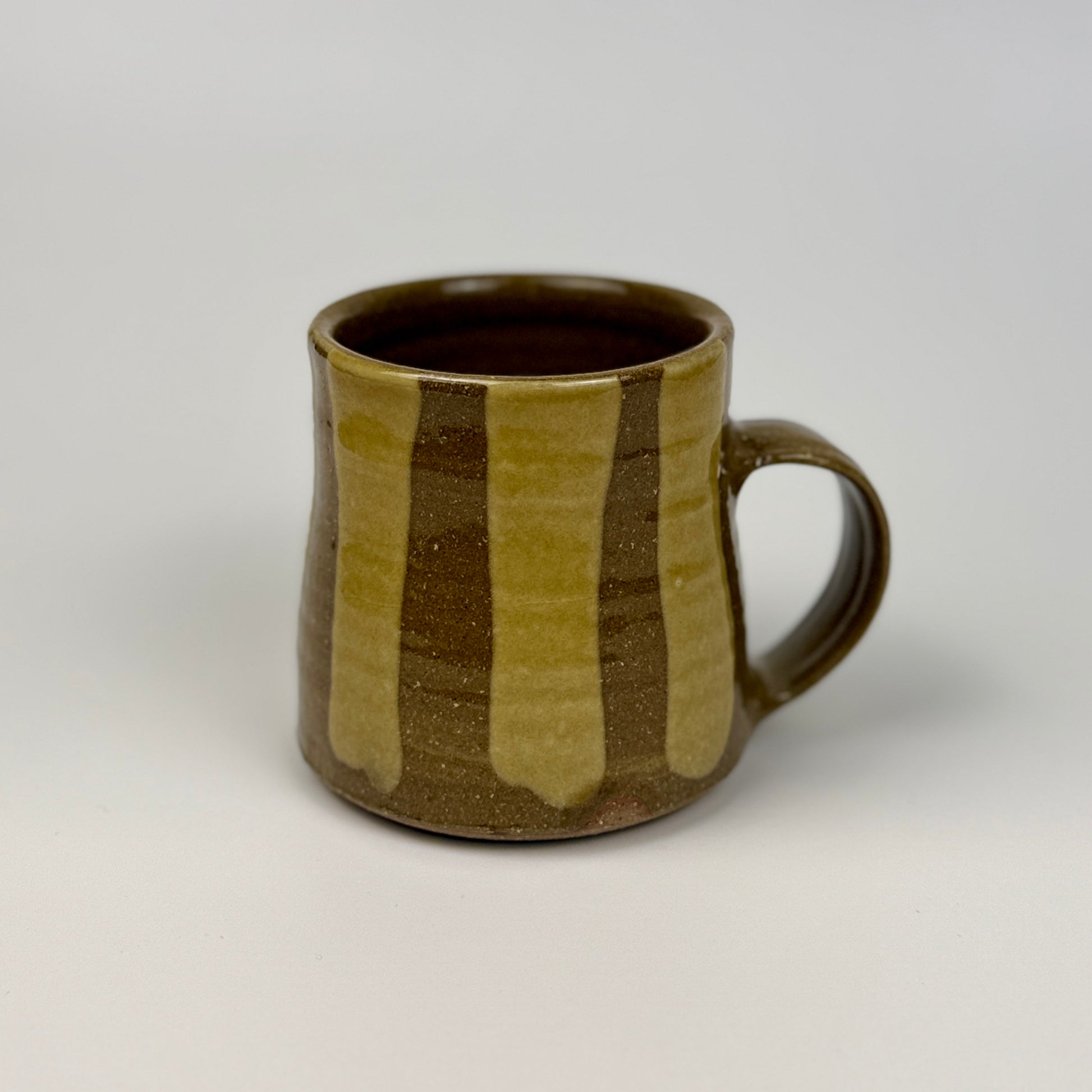 Ceramic mug with brown and beige stripes on a white background