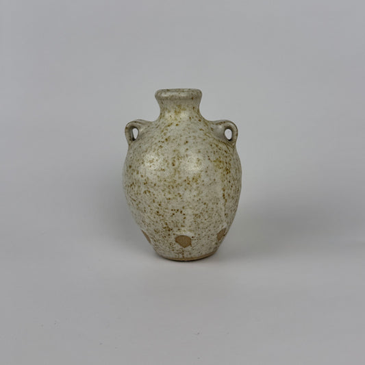Small ceramic vase with speckled glaze on a gray background