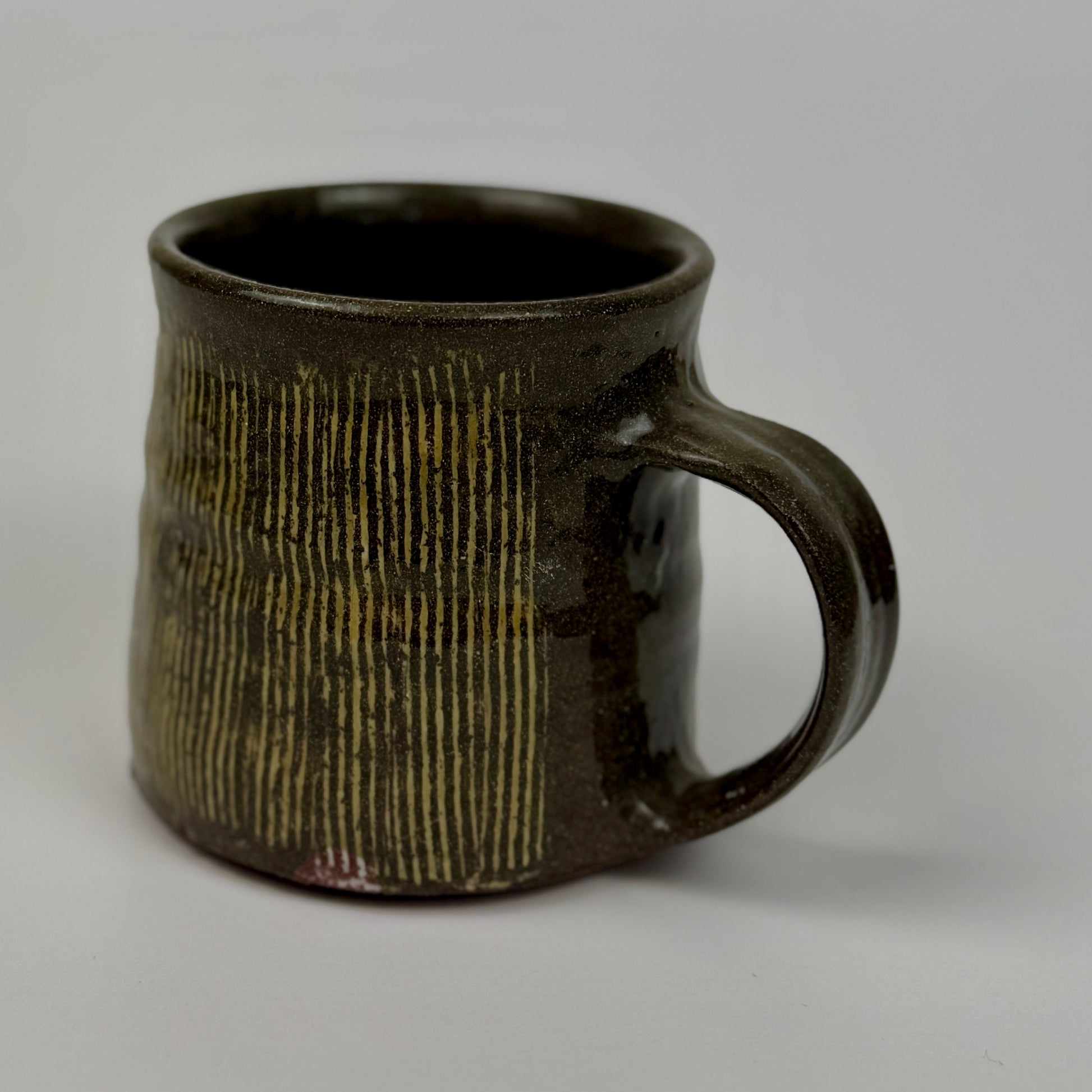 Dark brown ceramic mug with textured surface on a light gray background