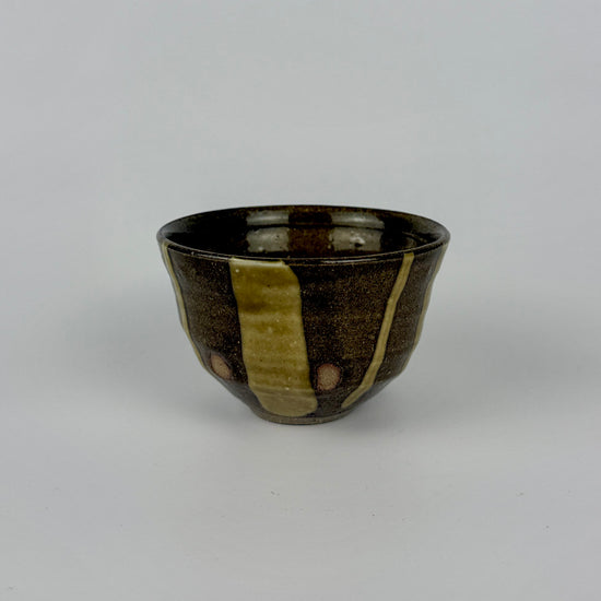 Ceramic cup with brown and green stripes on a white background