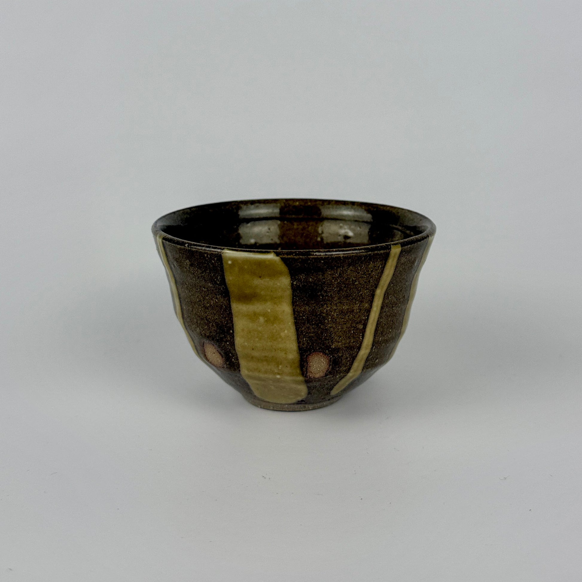 Ceramic cup with brown and green stripes on a white background