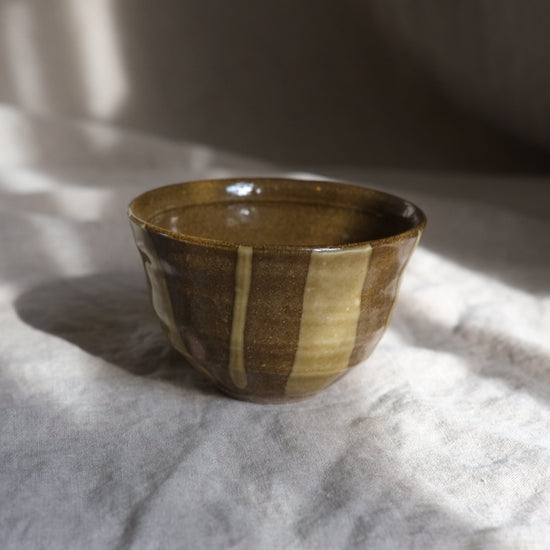 Ceramic bowl with striped design on a textured surface