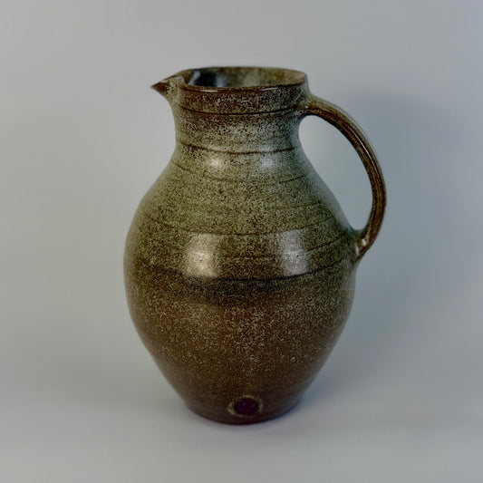 Brown ceramic pitcher on a gray background