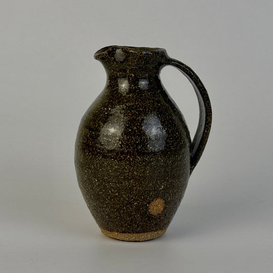 Brown speckled ceramic pitcher on a gray background
