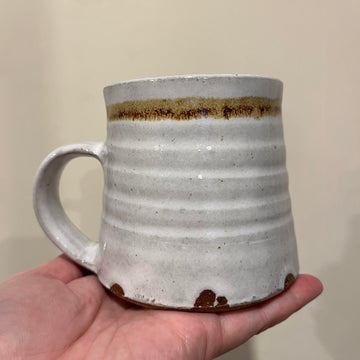 Hand holding a grey ceramic mug with a brown accent against a plain background