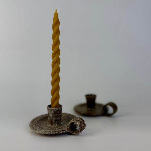 Twisted candle on a cermamic candle holder against a white background