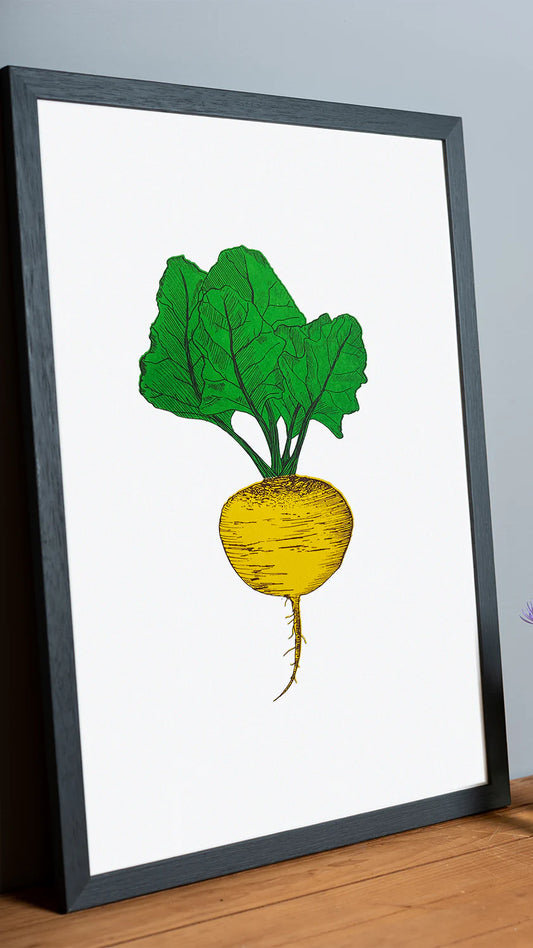 Framed artwork of a yellow root vegetable with green leaves on a white background