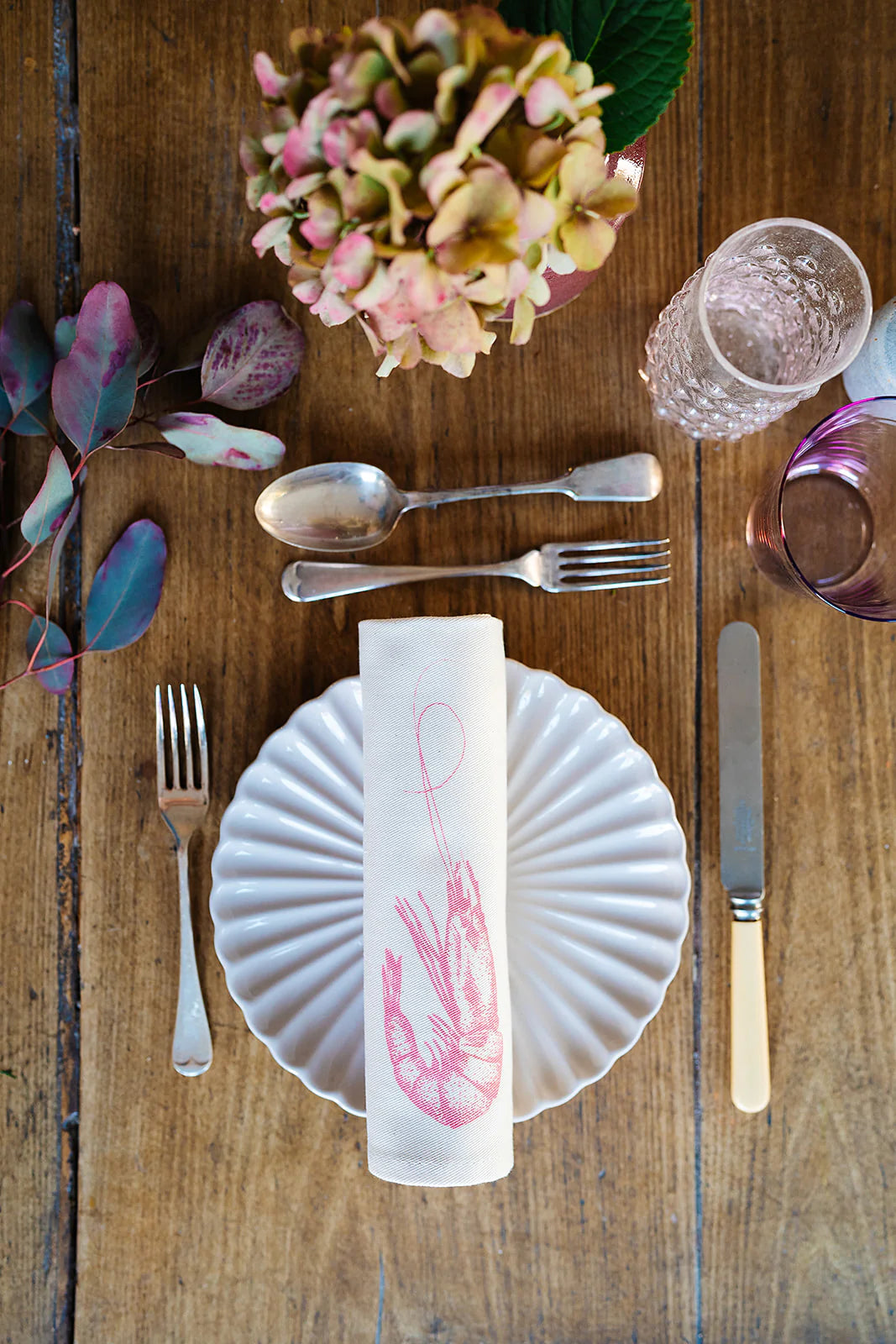 a set table featuring a rolled up napkin with prawn illustration