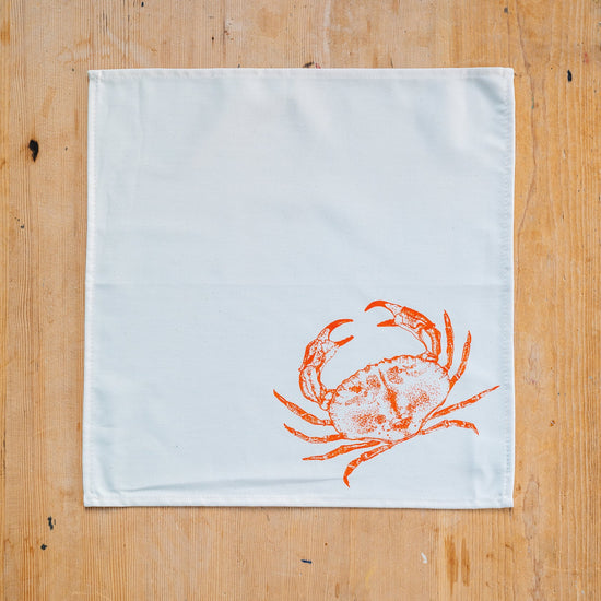 White towel with orange crab design on a wooden surface