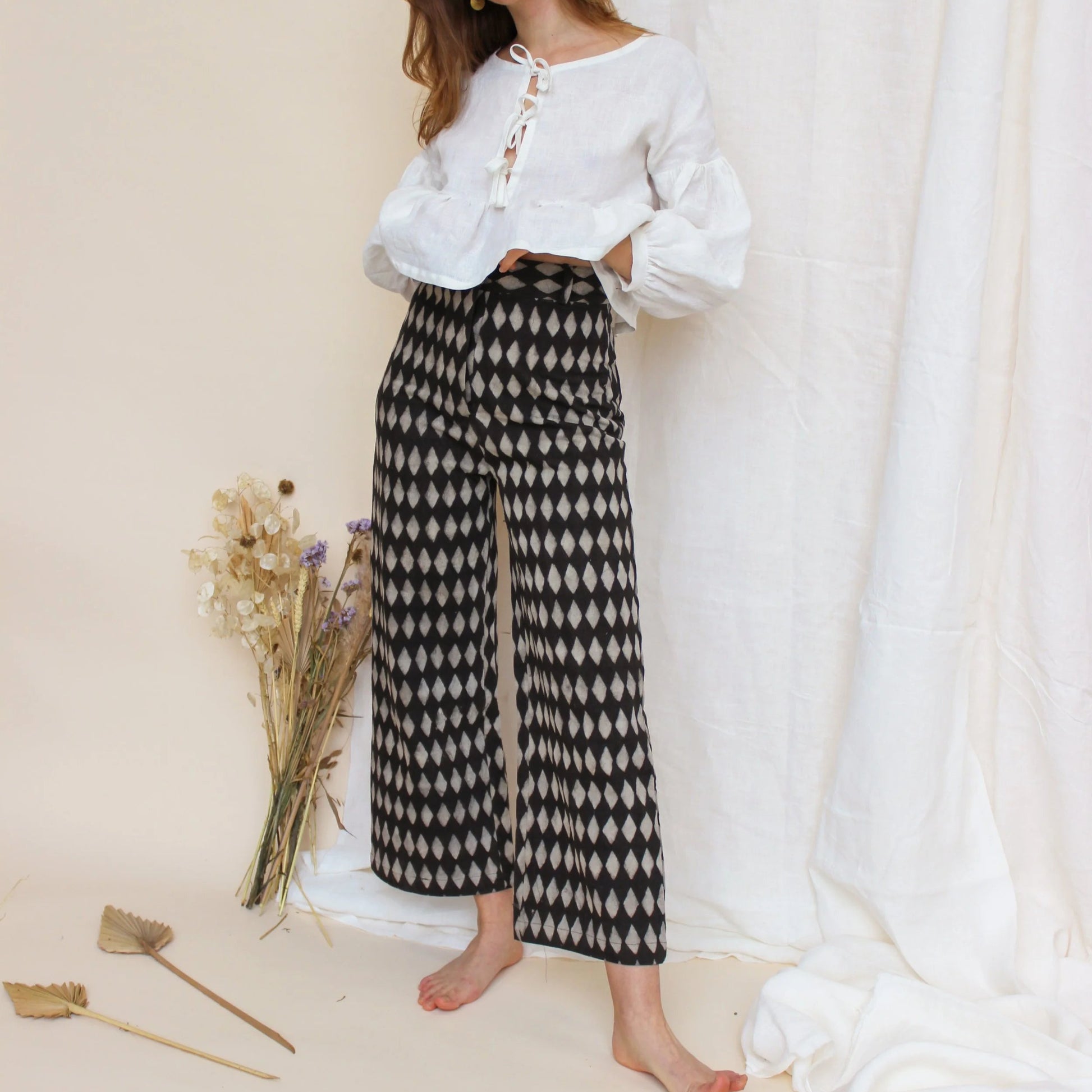Woman wearing heavily patterned trousers on a white background 