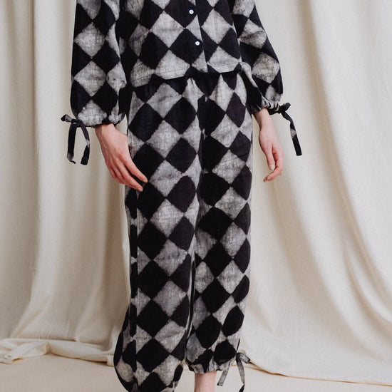 Person wearing a black and white checkered outfit against a plain background