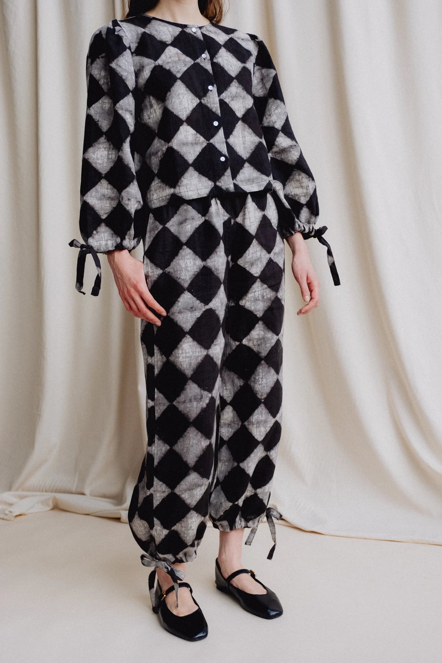 Person wearing a black and white checkered outfit against a plain background