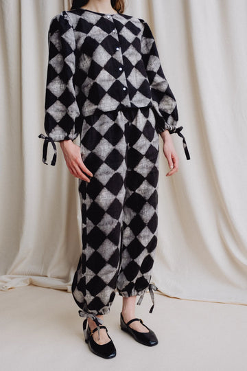 Person wearing a black and white checkered outfit against a plain background