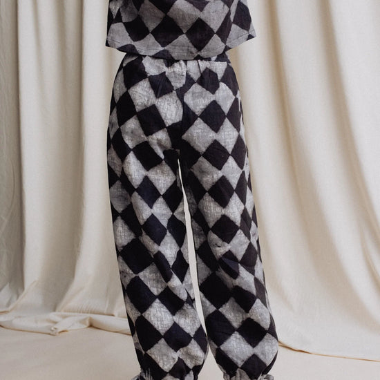 Person wearing a black and white checkered outfit against a plain background