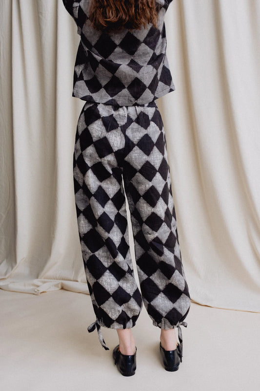 Person wearing a black and white checkered outfit against a plain background