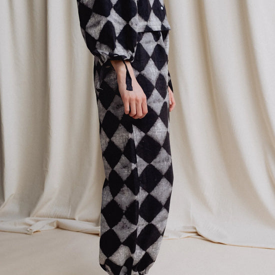 Person wearing a black and white checkered outfit with a plain background