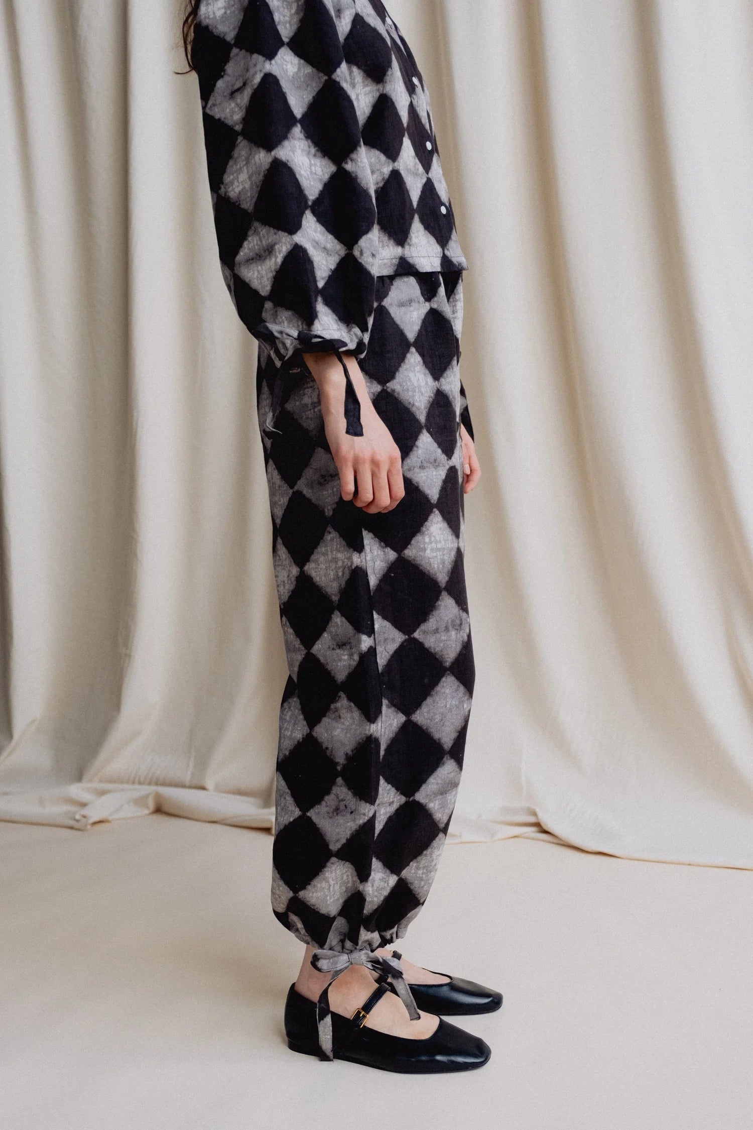 Person wearing a black and white checkered outfit with a plain background