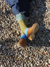 Load image into Gallery viewer, Person wearing brown shoes and multicolored socks on a gravel surface
