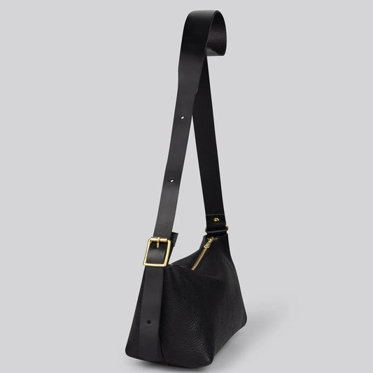 A black textured leather shoulder bag with a wide adjustable strap and gold-tone hardware, shown on a solid gray background.