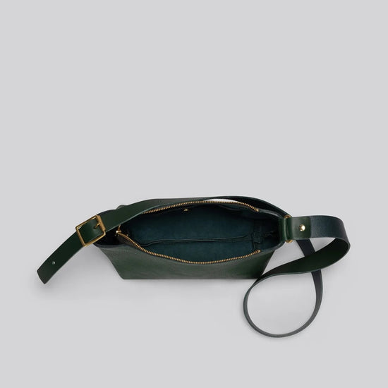 A dark green leather crossbody bag with a gold-tone zipper and hardware, shown open against a solid light gray background.