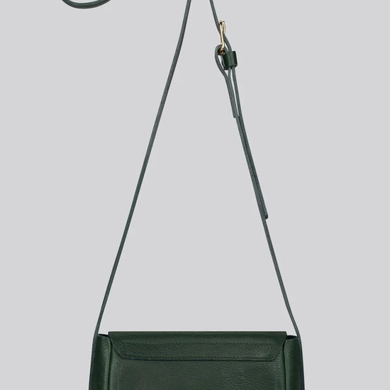 A dark green leather crossbody bag with a long adjustable strap, shown against a solid light gry background.