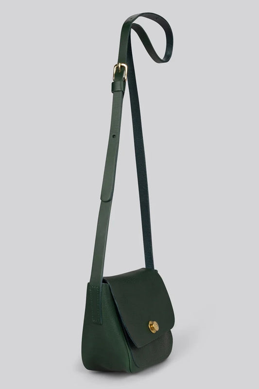 A dark green leather crossbody bag with a long adjustable strap and a small gold-tone turn-lock clasp, shown against a solid light gray background.