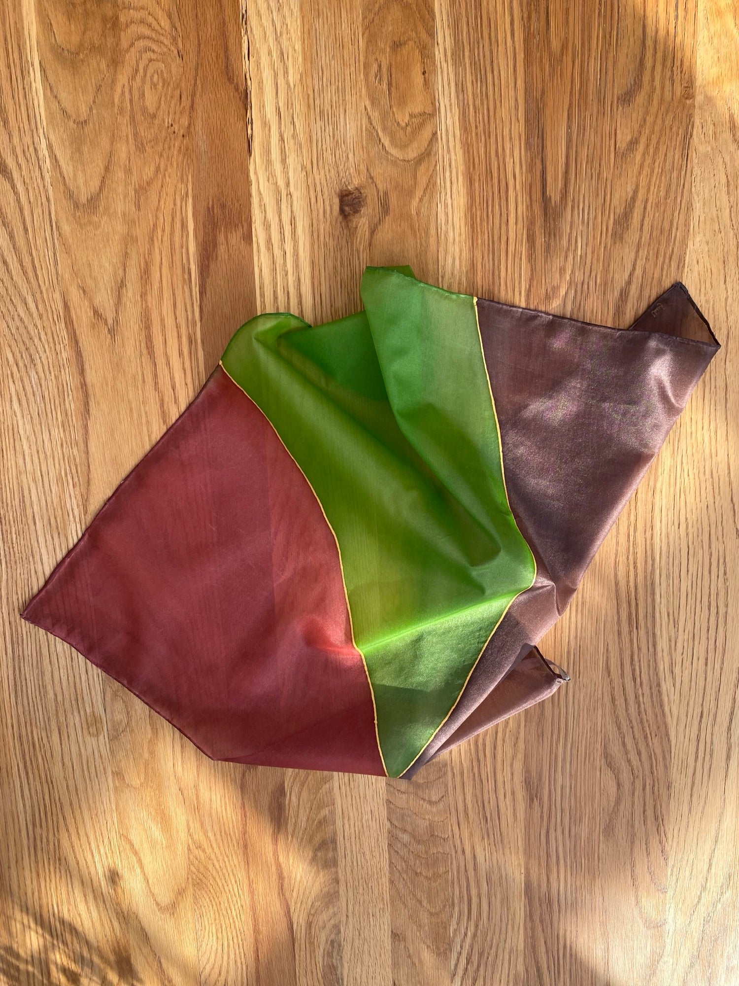 Folded fabric with red, green, and brown colors on a wooden surface