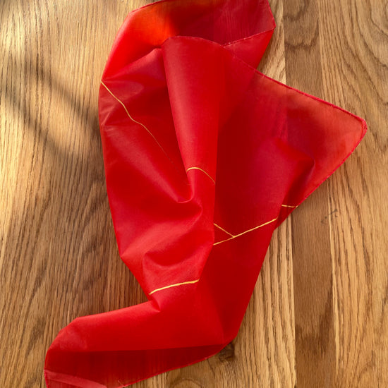Red silk scarf with gold trim on a wooden surface