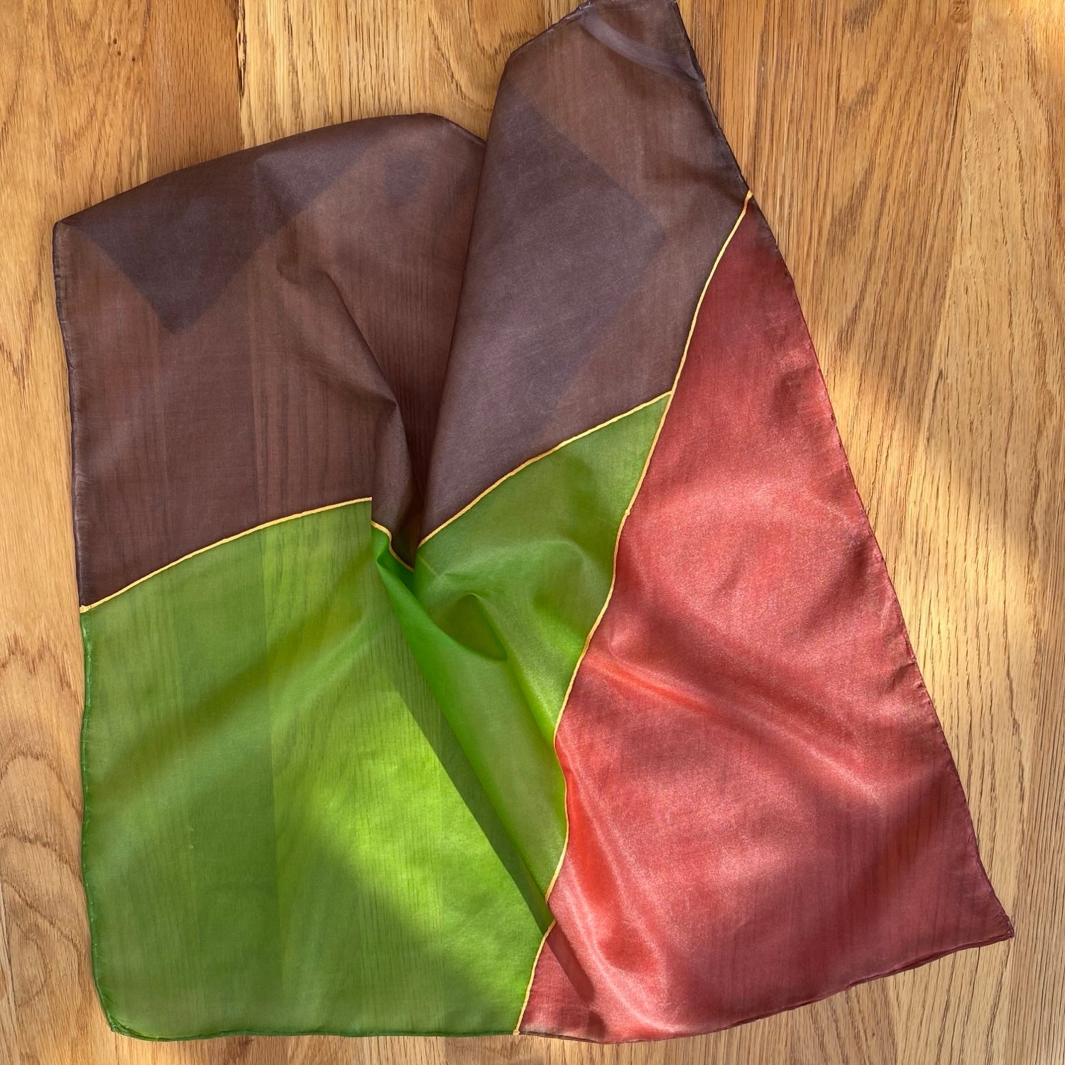 Multicolored fabric with brown, green, and red sections on a wooden surface