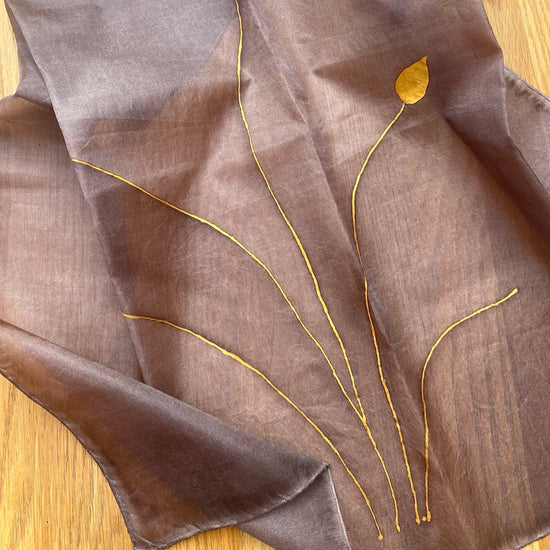Brown fabric with gold leaf designs on a wooden surface