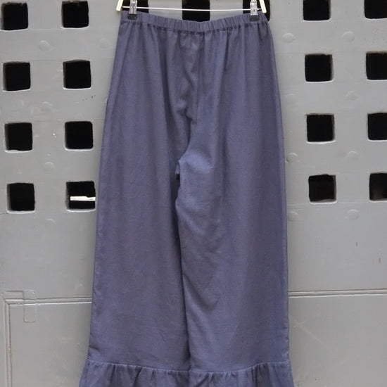 Navy trousers with frill hem on a grey door background 