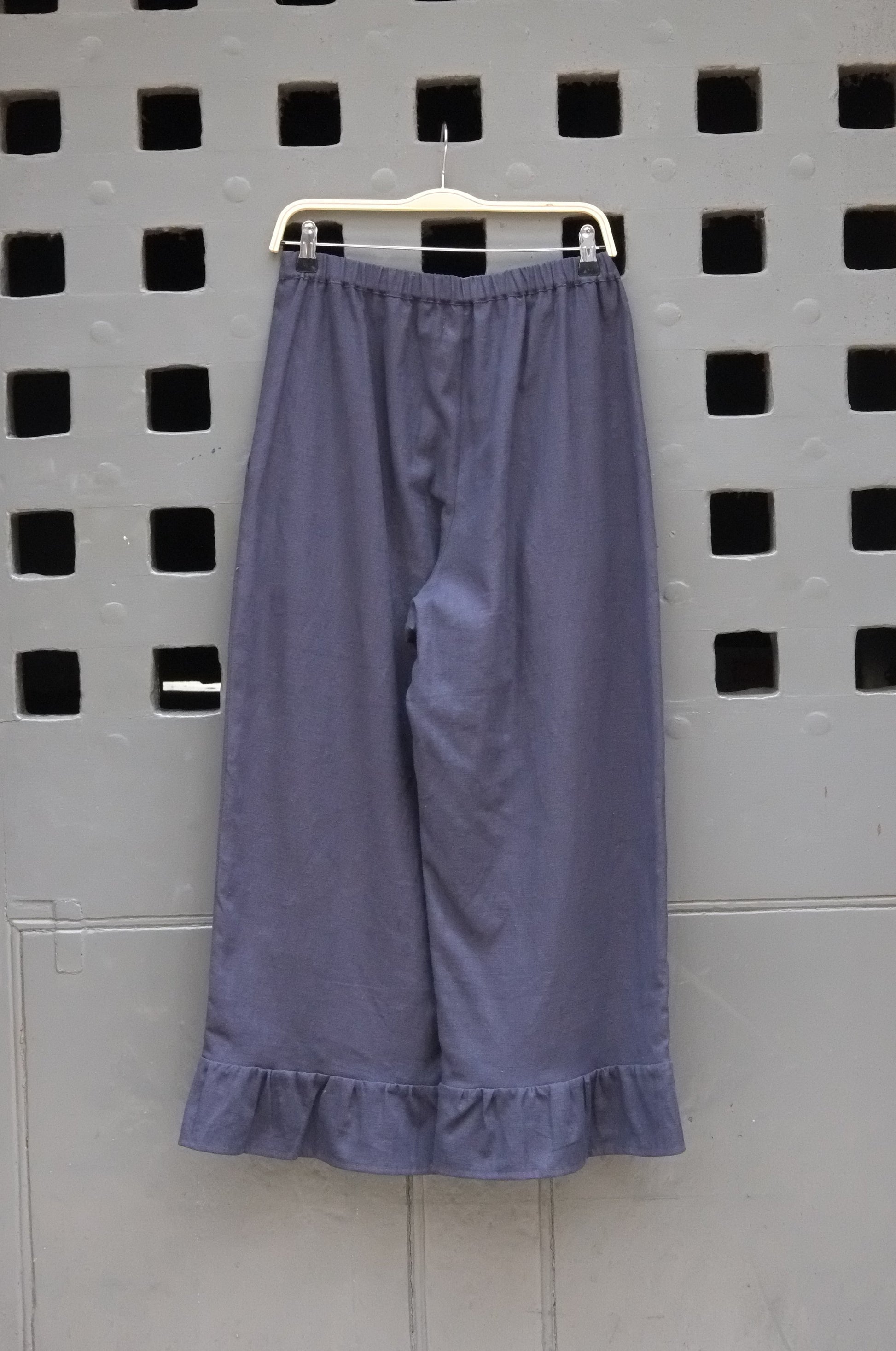 Navy trousers with frill hem on a grey door background 