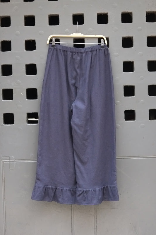 Navy trousers with frill hem on a grey door background 