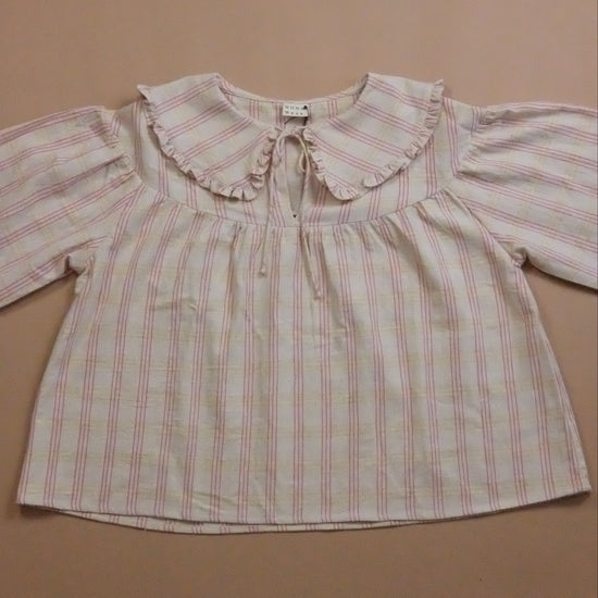 Striped blouse with ruffled collar and tie neck on a beige background