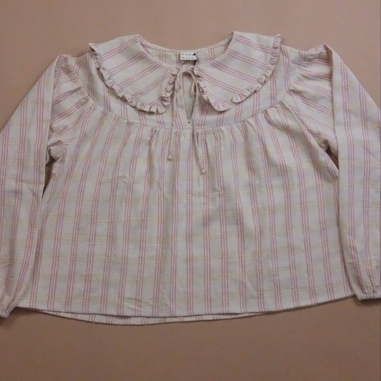 Plaid blouse with ruffled collar and tie neck on a beige background