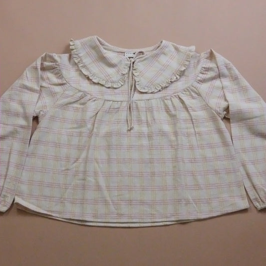 Plaid blouse with ruffled collar and tie neck on a beige background