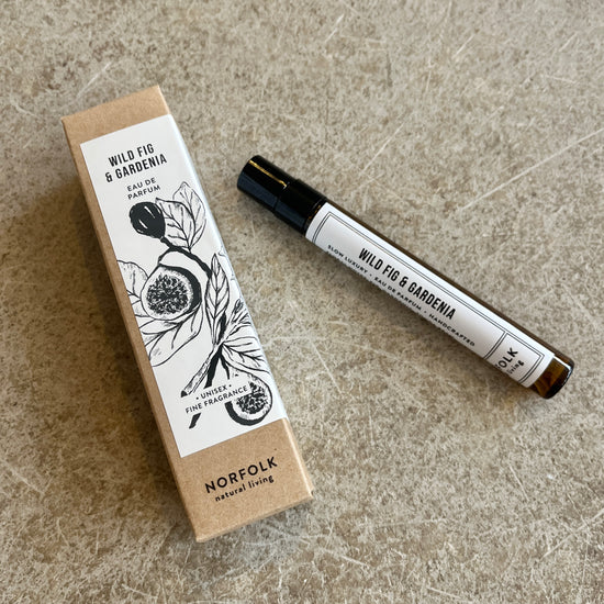 A 10ml parfum bottle with 'Wild Fig & Gardenia' labeled, alongside its packaging featuring botanical illustrations.