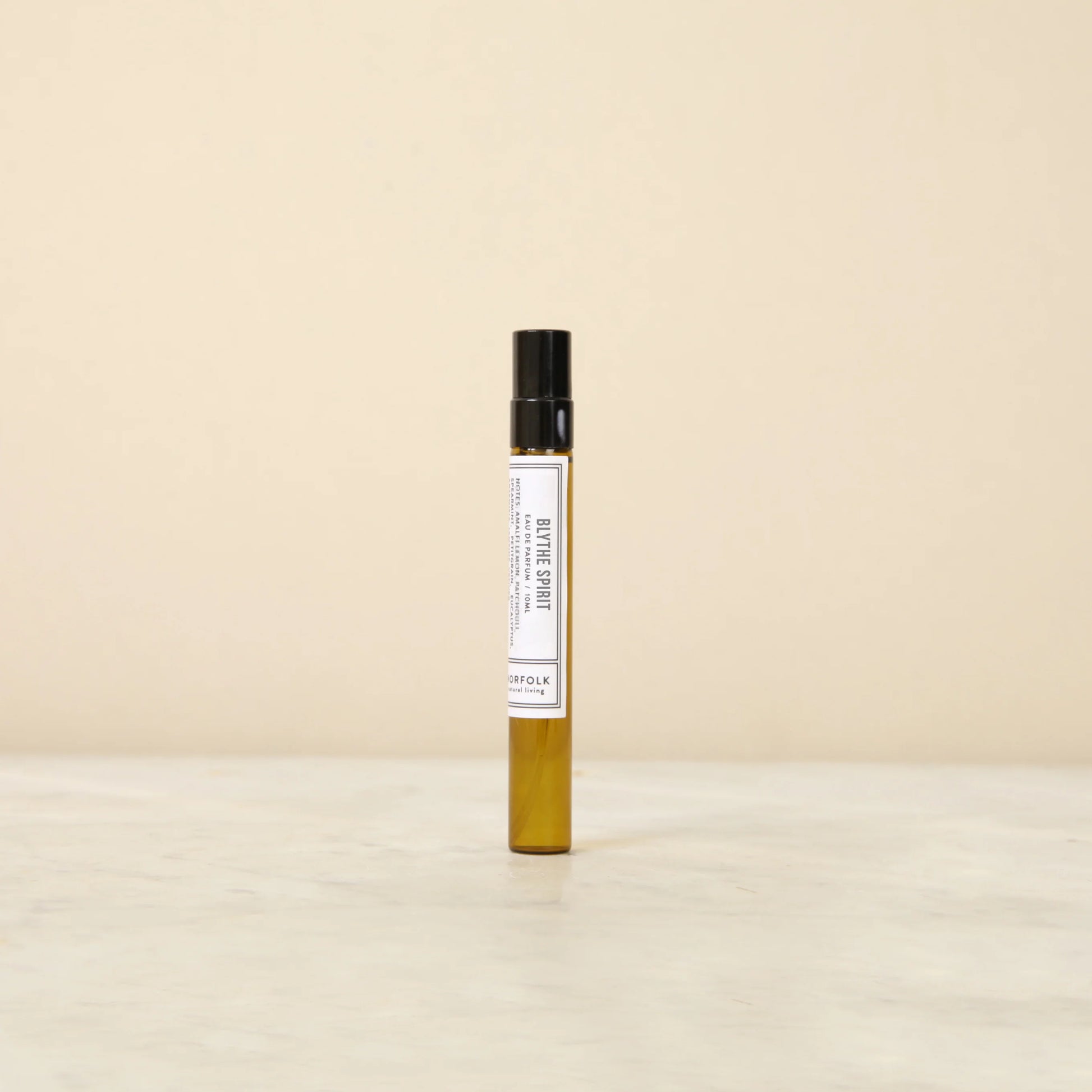 Small perfume bottle with a white label on a beige background