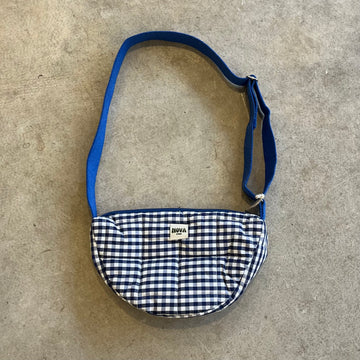 Small bag with blue checkered pattern and blue strap on a concrete surface