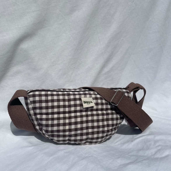 Plaid-patterned waist bag with brown strap on a light gray background