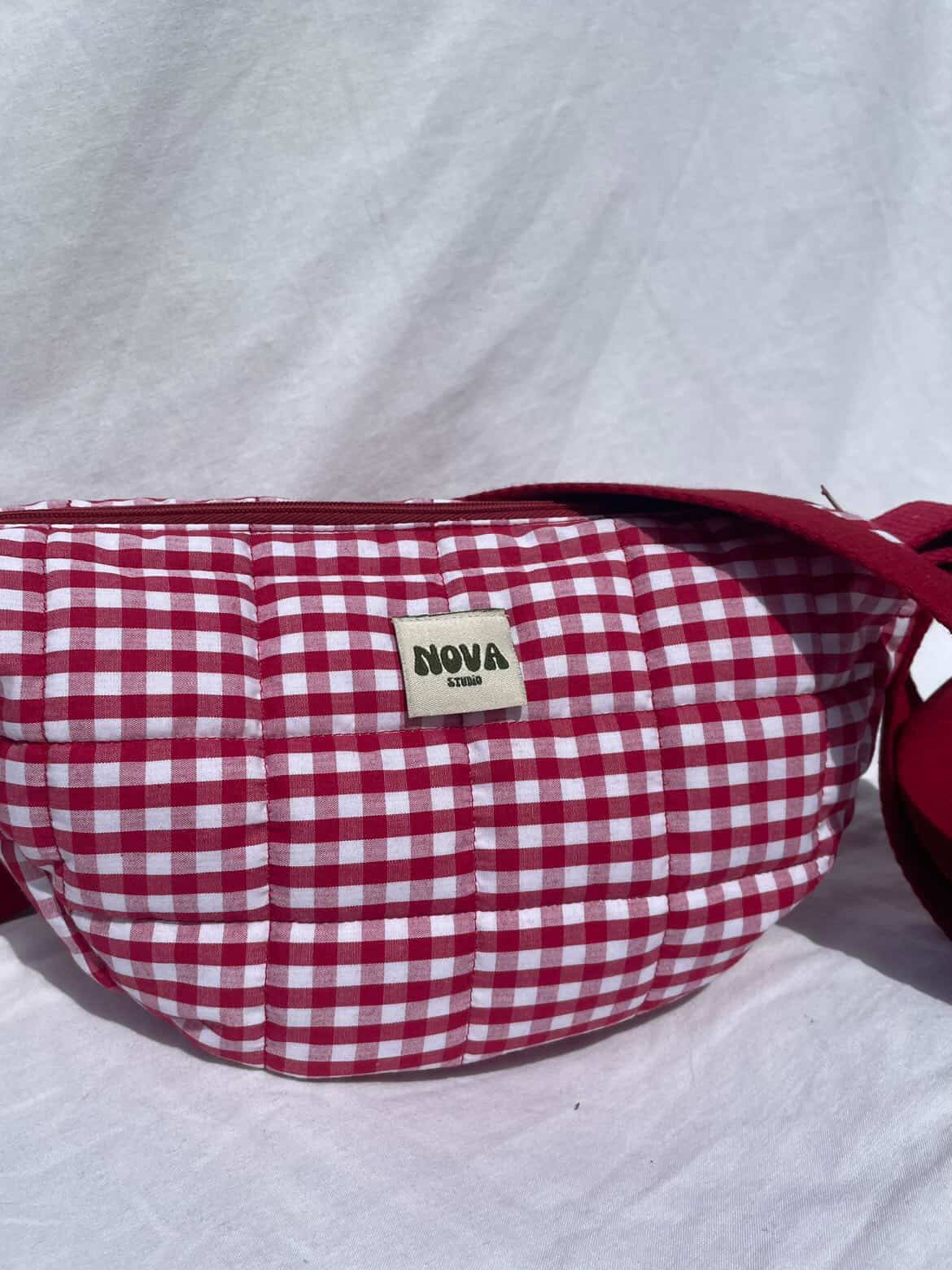 Red and white checkered bag with 'Nova' label on a light gray background